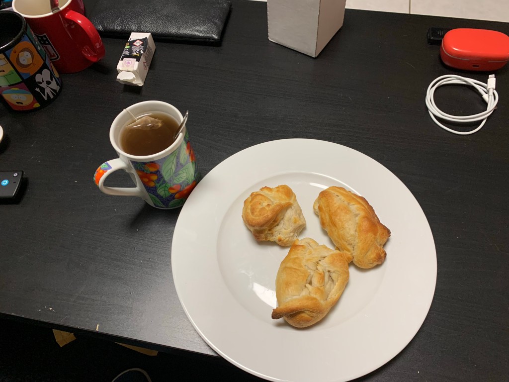 Das Foto zeigt einen Teller, wo selbst gemachter Croissants drauf liegen und eine Tasse mit Tee ￼