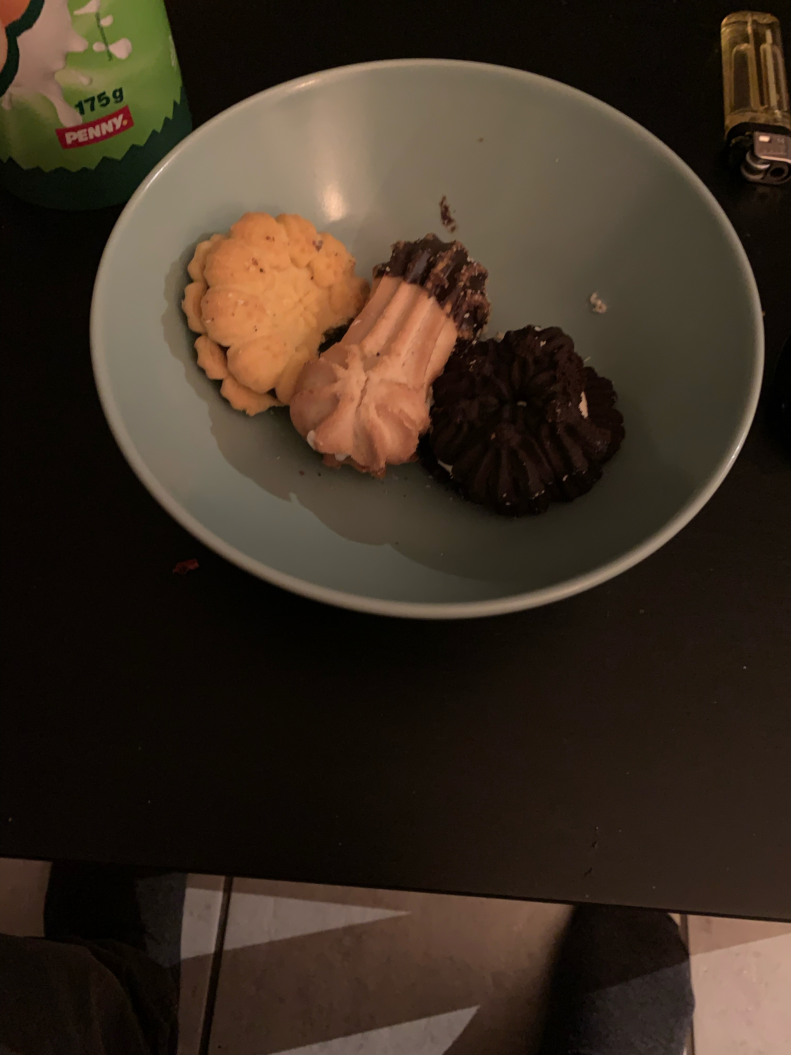 Es ist eine Schüssel mit drei Keksen ganz rechts außen liegt ein dunkler Keks, der mich an Oreo Kekse erinnert. Die anderen beiden sind mehr so Butter Kekse